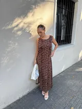 Vestido largo azul marino de tejido acanalado, con escote redondo y mangas cortas tipo hombrera. Presenta una abertura lateral en la falda.