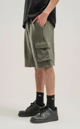 Bermuda de algodón rústico color verde militar, calce oversize, con elástico en la cintura y bolsillos cargo con cierre.