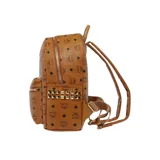 Mochila de lona revestida color marrón con monograma de la marca en toda la superficie, tachuelas metálicas doradas bordeando los bolsillos laterales, cierre bidireccional, asa superior reforzada, correas ajustables, dos compartimientos en la parte interior uno de ellos ideal para trasladar una tablet, bolsillos interior y exterior con cierre y placa metálica grabada con el nombre de la marca en la parte frontal.