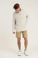 Sweater de punto color crema con cuello alto y cierre de cremallera parcial. Diseño de corte holgado y mangas largas.