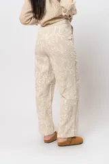Pantalón de corte recto color marrón con bordado floral blanco.