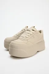 Zapatillas deportivas color beige con plataforma de 6 cm y cierre con cordones.