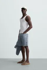 Musculosa blanca de algodón con cuello redondo y sisas amplias, corte ajustado.