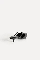Zapato destalonado tipo mule de cuero negro, con punta fina, tira delantera con hebilla y tacón kitten.