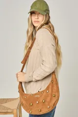 Cartera bandolera de cuero color celeste, con forma de media luna y tachas doradas decorativas. Posee correa ajustable y placa con logo en el frente.