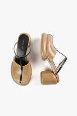 Mule color caramelo con plataforma y taco cilíndrico, tira superior negra y puntera cuadrada.