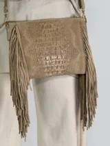 Bandolera color beige con textura símil piel de cocodrilo, flecos laterales y correa larga regulable.