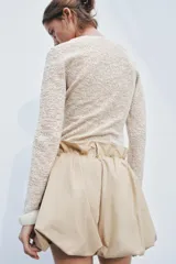 Top de punto color beige con textura, cuello redondo y manga larga.