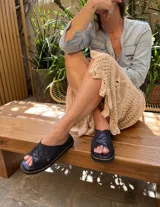 Sandalias bajas con tiras cruzadas color azul con textura brillante.