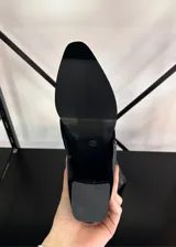 Botas de caña alta color negro, de cuero sintético, con punta fina y taco bajo.