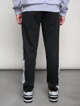 Pantalón de jogging negro con puños ajustados, cortes laterales y cambio de color en la parte inferior de la pierna.