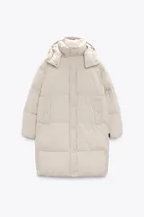 Cazadora larga acolchada color beige, de cuello subido y manga larga con puño elástico interior. Capucha desmontable con cremallera. Bolsillos en delantero con forro polar y botón a presión. Cierre frontal con cremallera oculta por solapa y botones a presión.