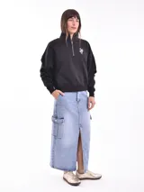 Buzo negro de corte cropped con cuello alto y cierre metálico plateado hasta el pecho. Tiene un pequeño bordado blanco con forma de serpiente en el lado izquierdo del pecho.