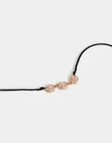 Collar corto con cordón negro y tres dijes de flores esmaltadas color rosa con borde dorado, unidas por eslabones dorados.