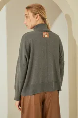Sweater negro oversize de tejido de punto, con cuello alto y detalle de costuras a la vista.