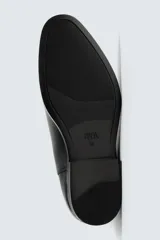 Bota estilo Chelsea de cuero negro, con punta fina, elásticos laterales y tirador trasero. Posee suela con ligero tacón.