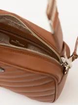 Bandolera color beige con diseño acolchado en forma de V y logo metálico dorado en forma de labios. Tiene correa larga ajustable y herrajes plateados.