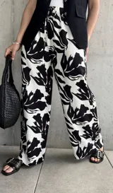 Pantalón palazzo de tiro alto con estampado floral abstracto en blanco y negro, con cintura elastizada y cordón ajustable.