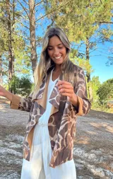 Parka o chaqueta ligera de mujer con cuello solapa y manga larga. Presenta un estampado animal print que combina tonos marrones, beige y detalles en celeste/turquesa.