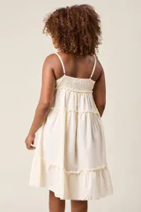 Vestido corto lila con breteles finos, escote en V con botones y falda escalonada con volados.