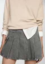 Minifalda gris de denim con diseño plisado y cierre lateral con cremallera.