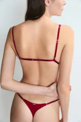 Colaless negro de tiro bajo con tiras finas laterales ajustables, decoradas con pequeños dijes metálicos en forma de corazón.