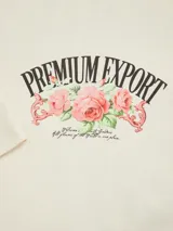 Camiseta color crema de manga corta y cuello redondo, con estampado frontal de rosas y texto "Premium Export".