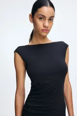 Vestido largo negro de punto elástico con leve brillo, corte entallado, escote drapeado, espalda escotada y pliegues laterales.