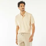 Remera tipo polo color crema, de piqué de algodón, con cuello clásico, tapeta de dos botones y mangas cortas con ribete.