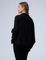 Cardigan negro de tejido suave, estilo poncho o capa, con cuello tipo chal y mangas amplias.