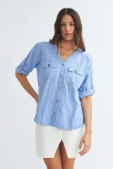 Camisa color crema de algodón con escote en V, mangas 3/4 con trabilla y dos bolsillos con solapa en el pecho.