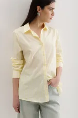 Camisa amarilla a rayas verticales blancas, de corte clásico, con cuello camisero y mangas largas.