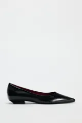 Zapato plano de charol negro con punta fina y suela baja.