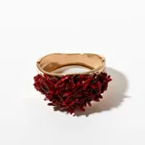 Brazalete rígido dorado con incrustaciones de coral rojo.