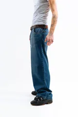 Pantalón de jean azul desgastado, corte mega baggy, con estampa serigrafiada en la pierna y botones personalizados.