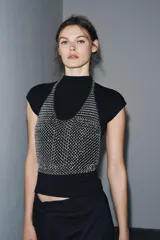 Top plateado de anillas metálicas con cuello halter y hombros descubiertos. Se cierra con mosquetón en cuello y espalda.