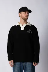 Sweater de punto verde con cuello polo color crema y bordado frontal con texto en blanco.