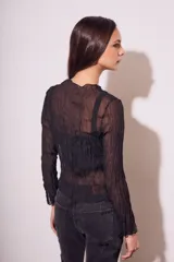 Blusa negra traslúcida de viscosa con textura arrugada, mangas largas acampanadas y escote en V con lazos.