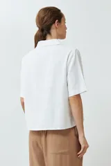 Blusa blanca de lino con cuello camisero y mangas cortas.