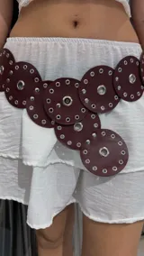 Cinturón marrón con discos de cuero sintético y ojalillos metálicos.