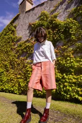 Bermuda a la rodilla con rayas verticales color salmón y gris. Tiene tiro medio, calce relajado, cierre con botones y ganchito oculto en la cintura, y bolsillos laterales.