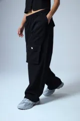 Pantalón cargo de denim negro, con cintura elástica y grandes bolsillos cargo a los lados con botones metálicos plateados.