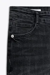 Jeans skinny de tiro alto en denim azul oscuro, con cinco bolsillos y cierre frontal con cremallera y botón metálico.