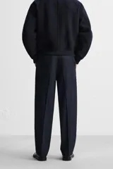 Pantalón de vestir azul marino, de corte recto, con bolsillos laterales y traseros. Incluye un bolsillo tipo cargo en la pierna izquierda. Se ajusta a la cintura con cinturón de cuero marrón.