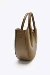 Bolso shopper de mano color marrón, con asa doble y correa bandolera extraíble. Tiene cierre imantado y un bolsillo interior con cremallera.