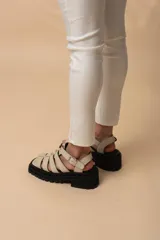 Sandalias de tiras anchas color blanco, con plataforma track negra y hebilla lateral ajustable.