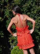 Pollera corta color marrón rojizo, con textura arrugada y volados en el ruedo. Presenta detalles de costura negra en zigzag sobre los volados.