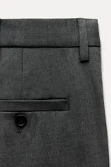 Pantalón de vestir gris oscuro de tiro bajo, con trabillas en la cintura, bolsillos delanteros y traseros, raya planchada y pierna recta.