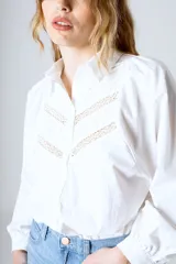 Camisa blanca de manga larga con detalles de encaje en el frente y cuello mao.