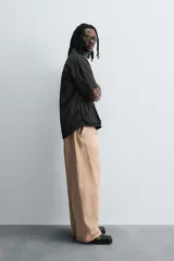 Pantalón de jean color beige, de corte ancho y tiro medio, con cinco bolsillos, efecto lavado y cierre frontal con cremallera y botón.